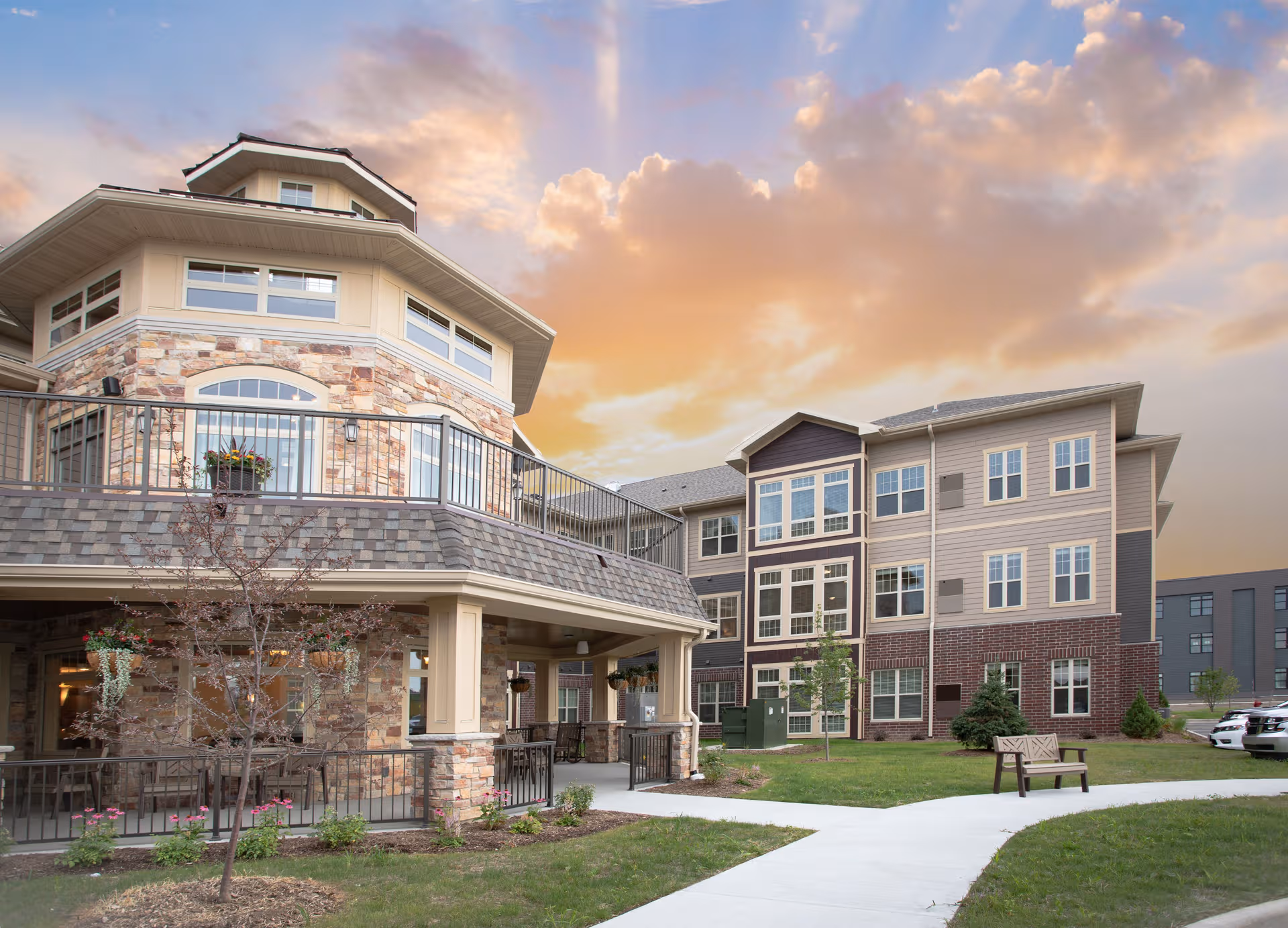 Modern senior living campus exterior featuring stone accents, balconies, and a paved walkway.