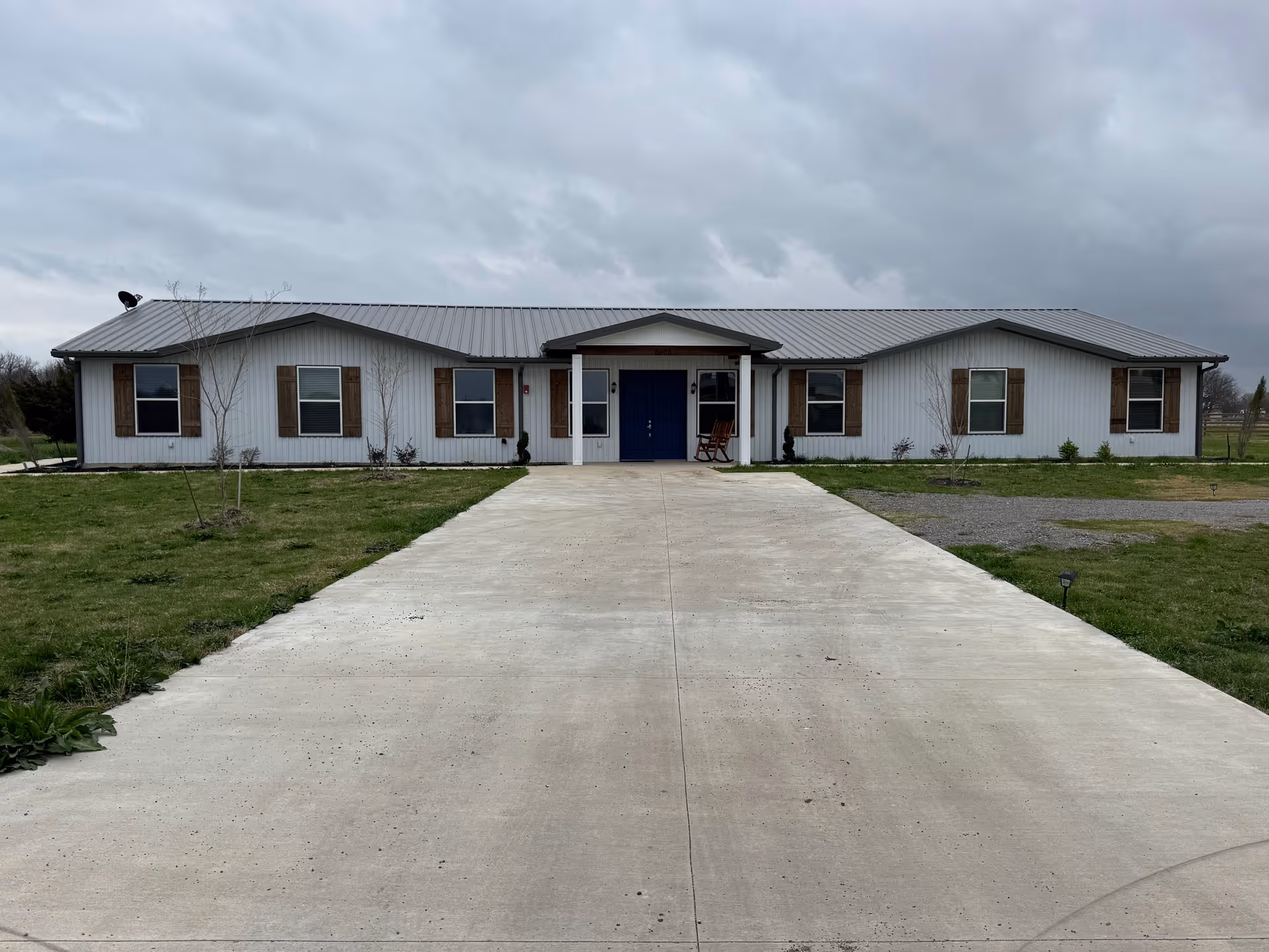 Front view of Sparks Assisted Living, a single-story building with blue door and long driveway.