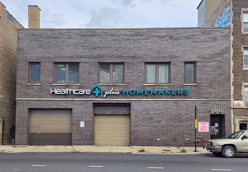 Brick building storefront with a sign reading Healthcare Plus Homemakers along a city street