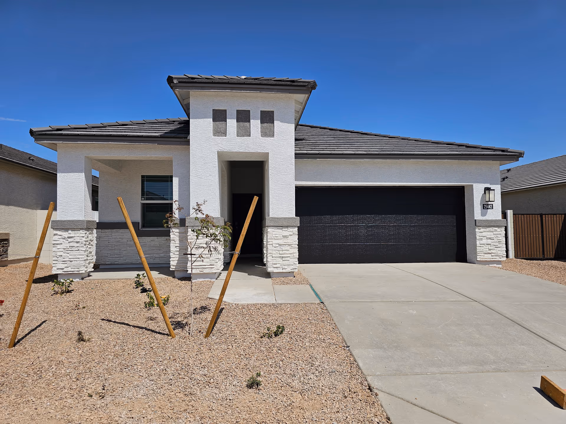 Front exterior of a modern single-story building with a two-car garage and gravel yard.