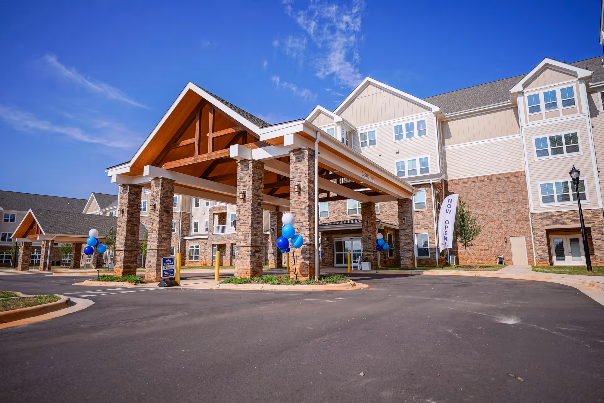 Exterior view of Harmony at Brookberry Farm, senior living facility, with a covered entrance and balloons.