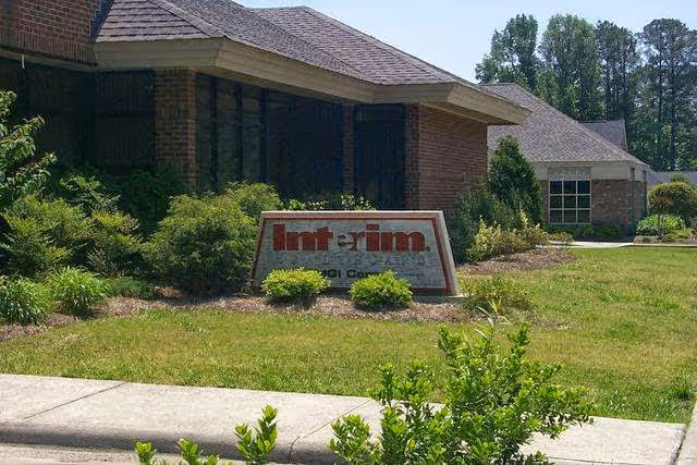 Exterior view of a senior living facility with a sign and landscaped front yard.