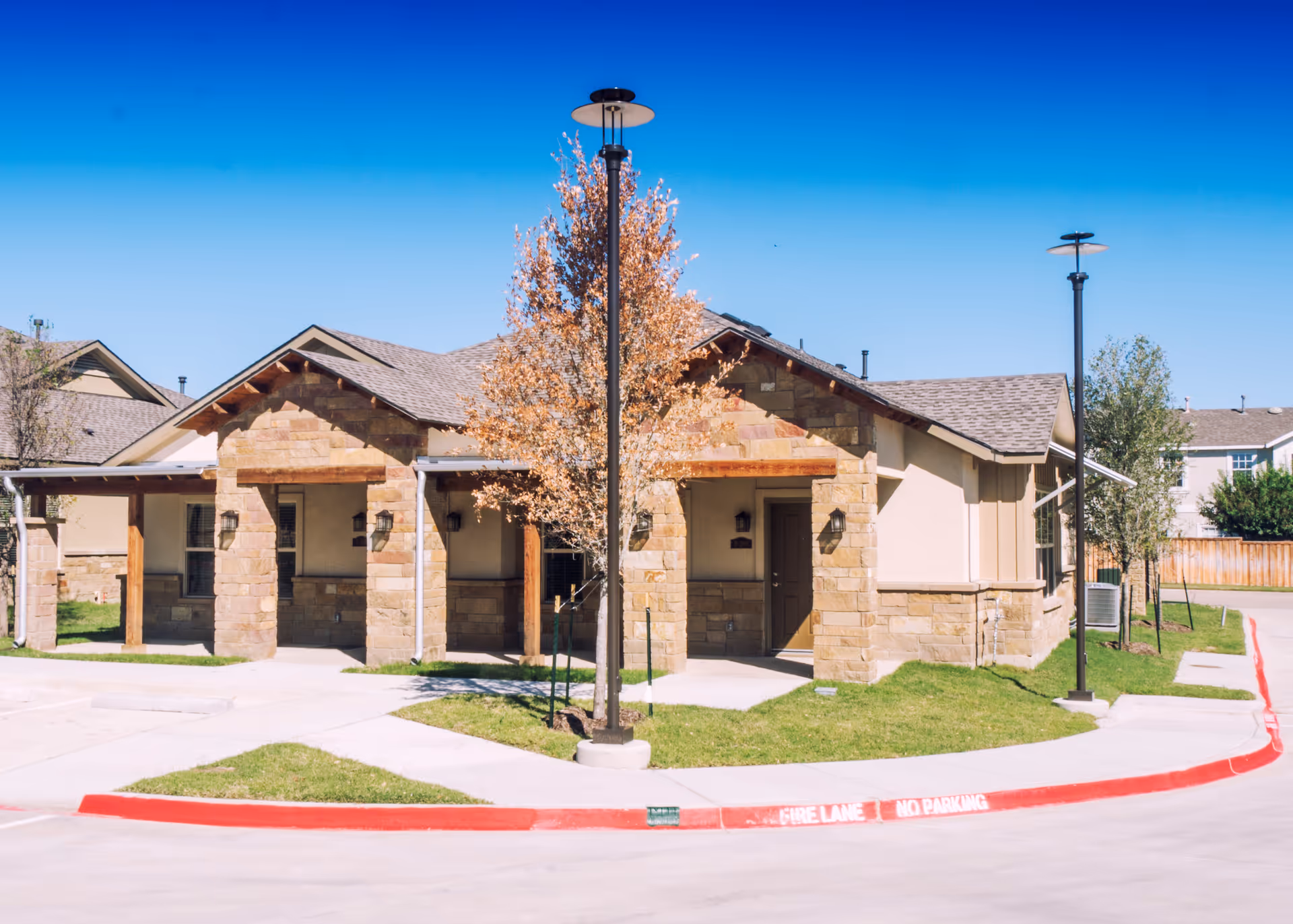 Single-story stone-clad facility exterior with entrance alcoves and manicured lawn.