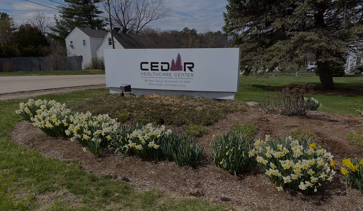 Outdoor view of a Cedar Healthcare Center sign with flower beds and mulch.
