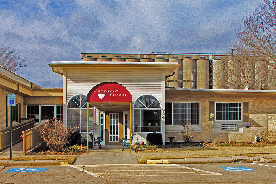 Front view of Cherished Friends senior living entrance with glass doors and seating.