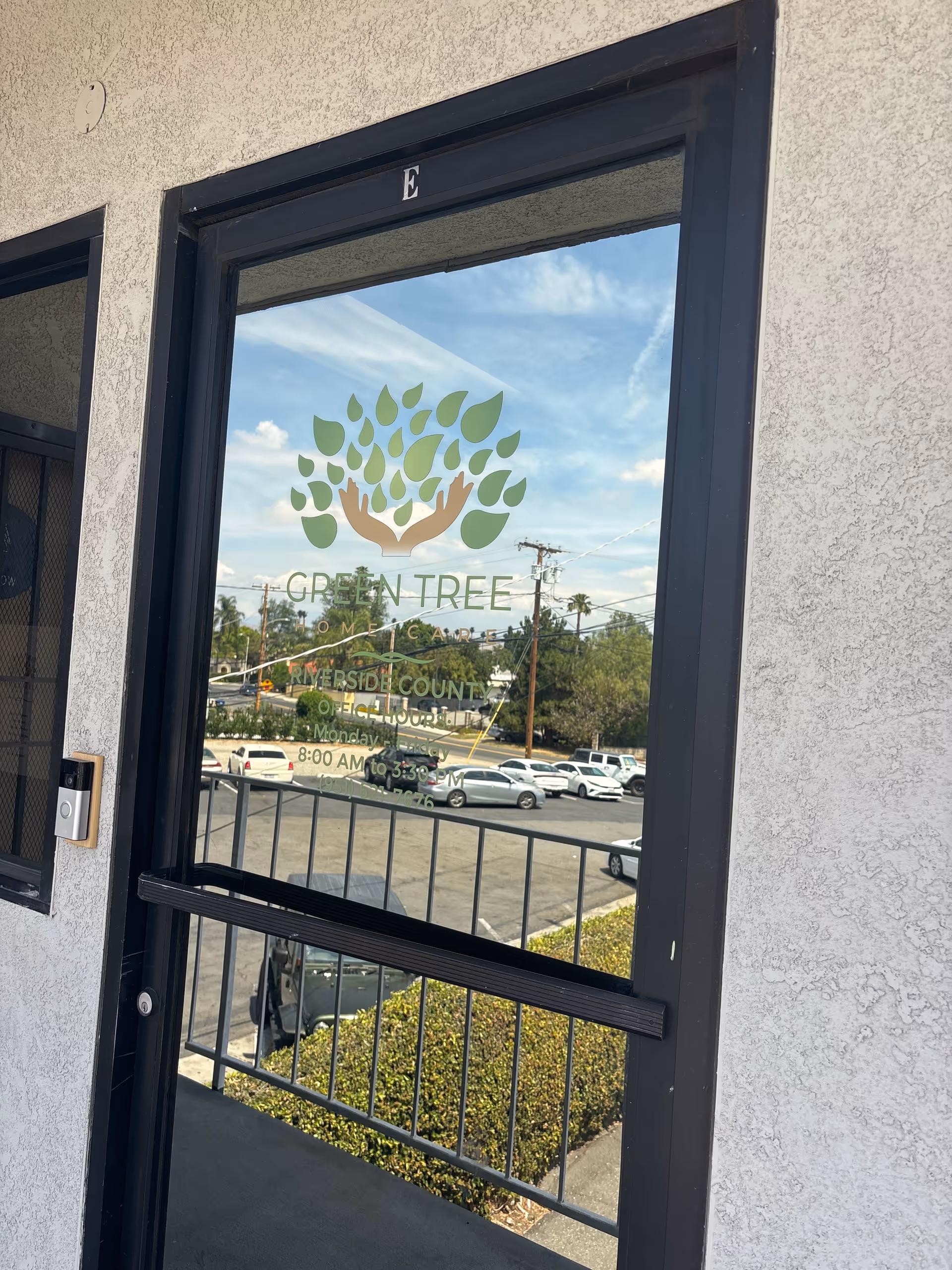 Glass door with Green Tree Home Care logo, exterior wall, and parking lot visible outside.