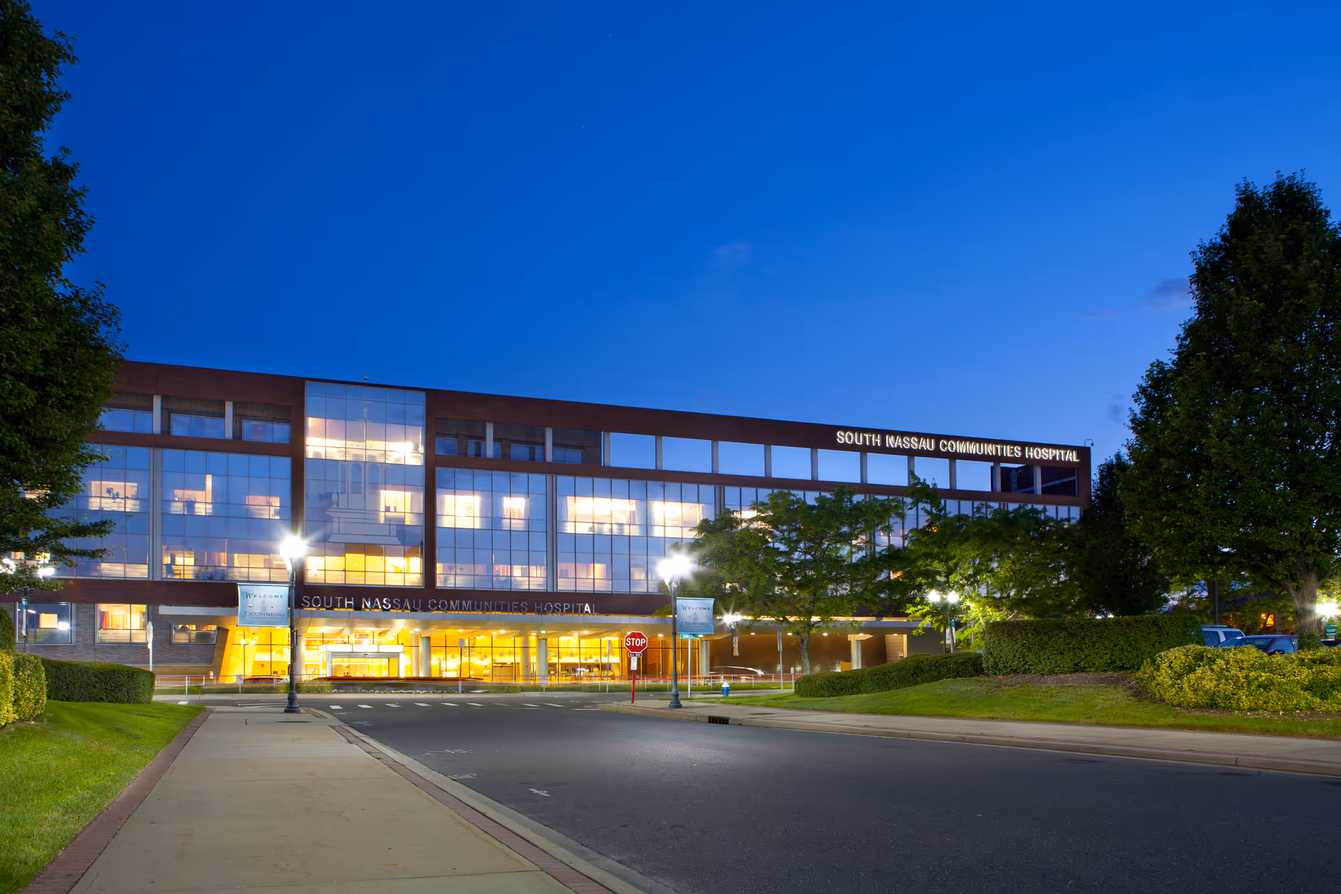 Exterior view of South Nassau Communities Hospital TCU at dusk with illuminated entrance.