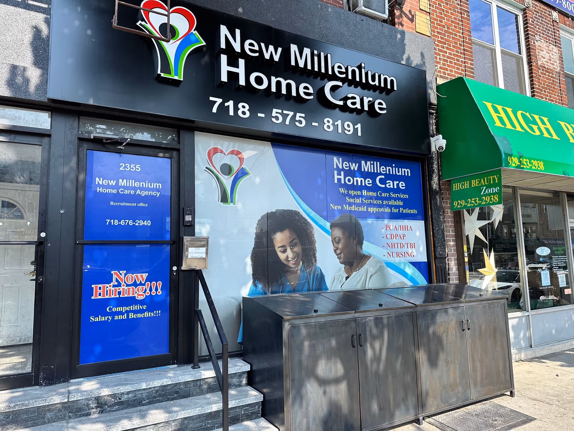 Storefront sign reads New Millenium Home Care with blue recruitment posters.
