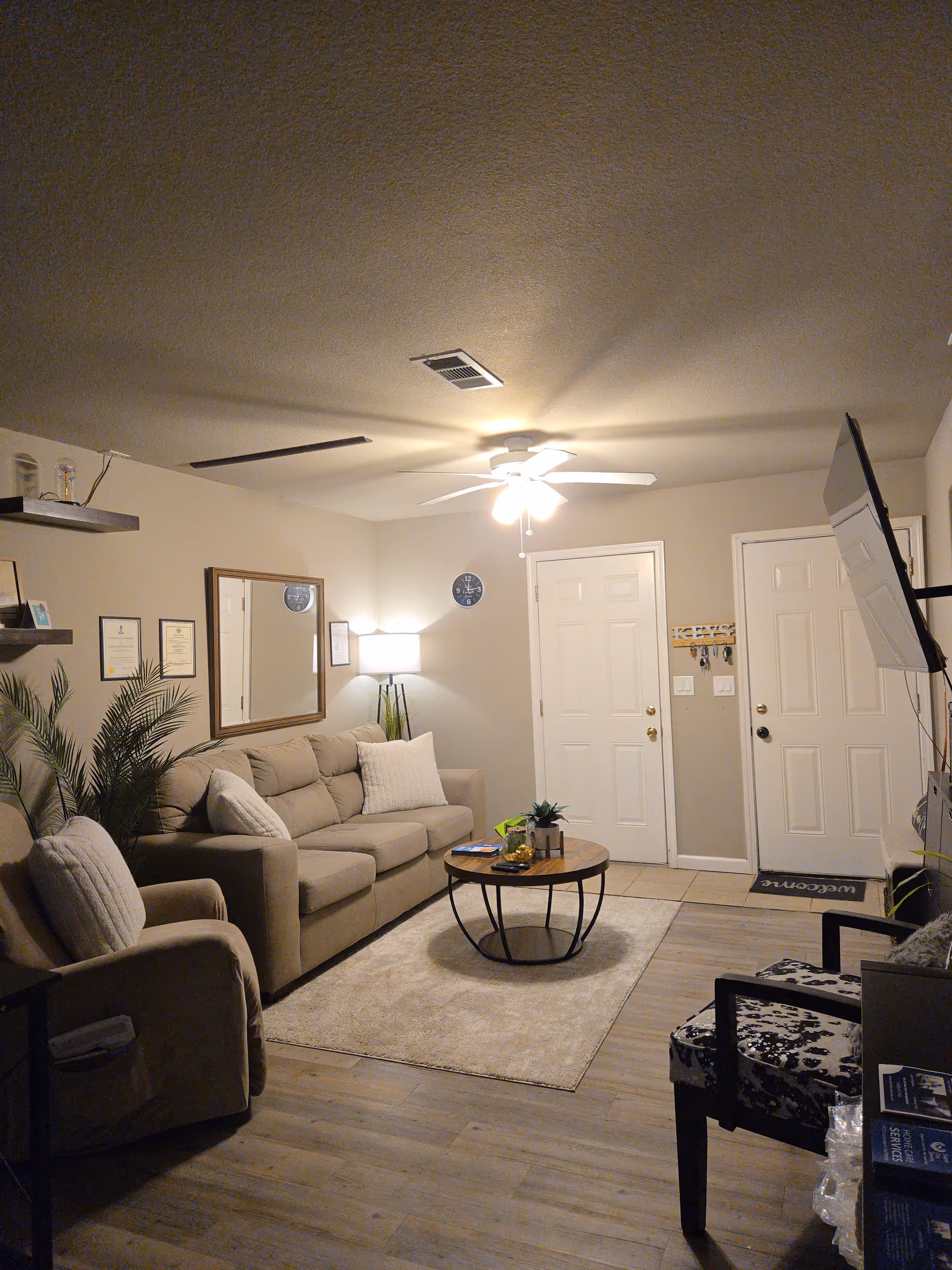 Cozy living room featuring beige sofa, chairs, coffee table, rug, and ceiling fan.