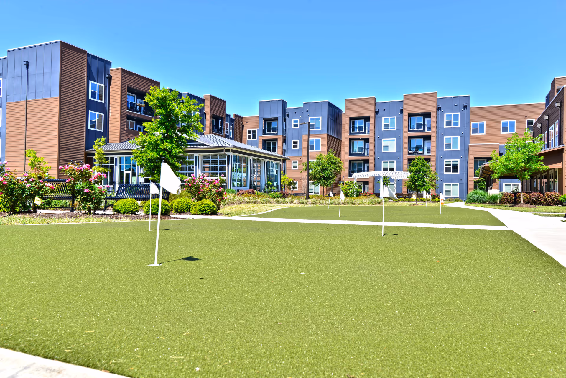 Exterior view of Inspire Sandhill senior living campus with a courtyard and putting green.