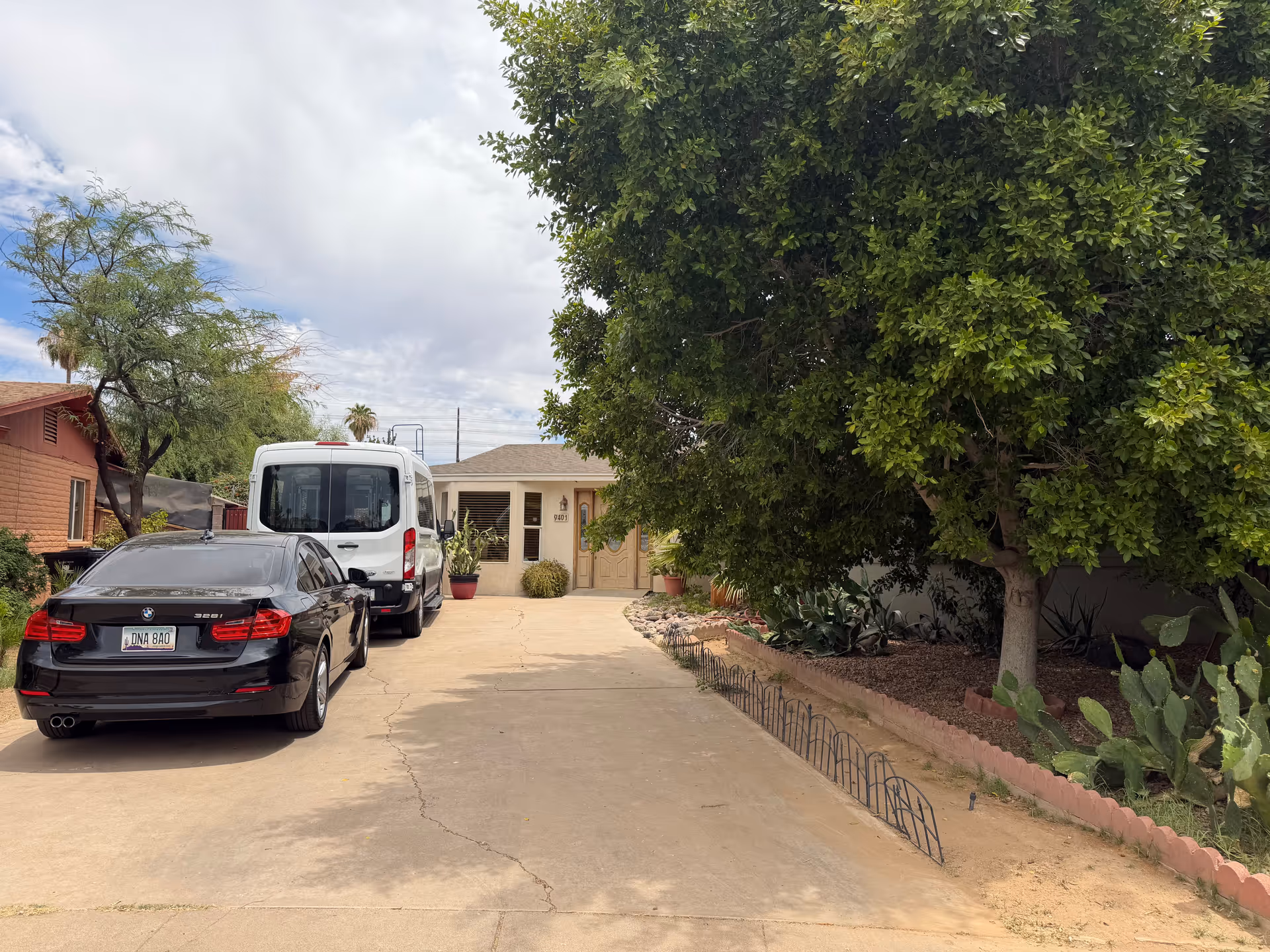 Driveway with two vehicles and a large tree in front of Desert View Adult Care Home