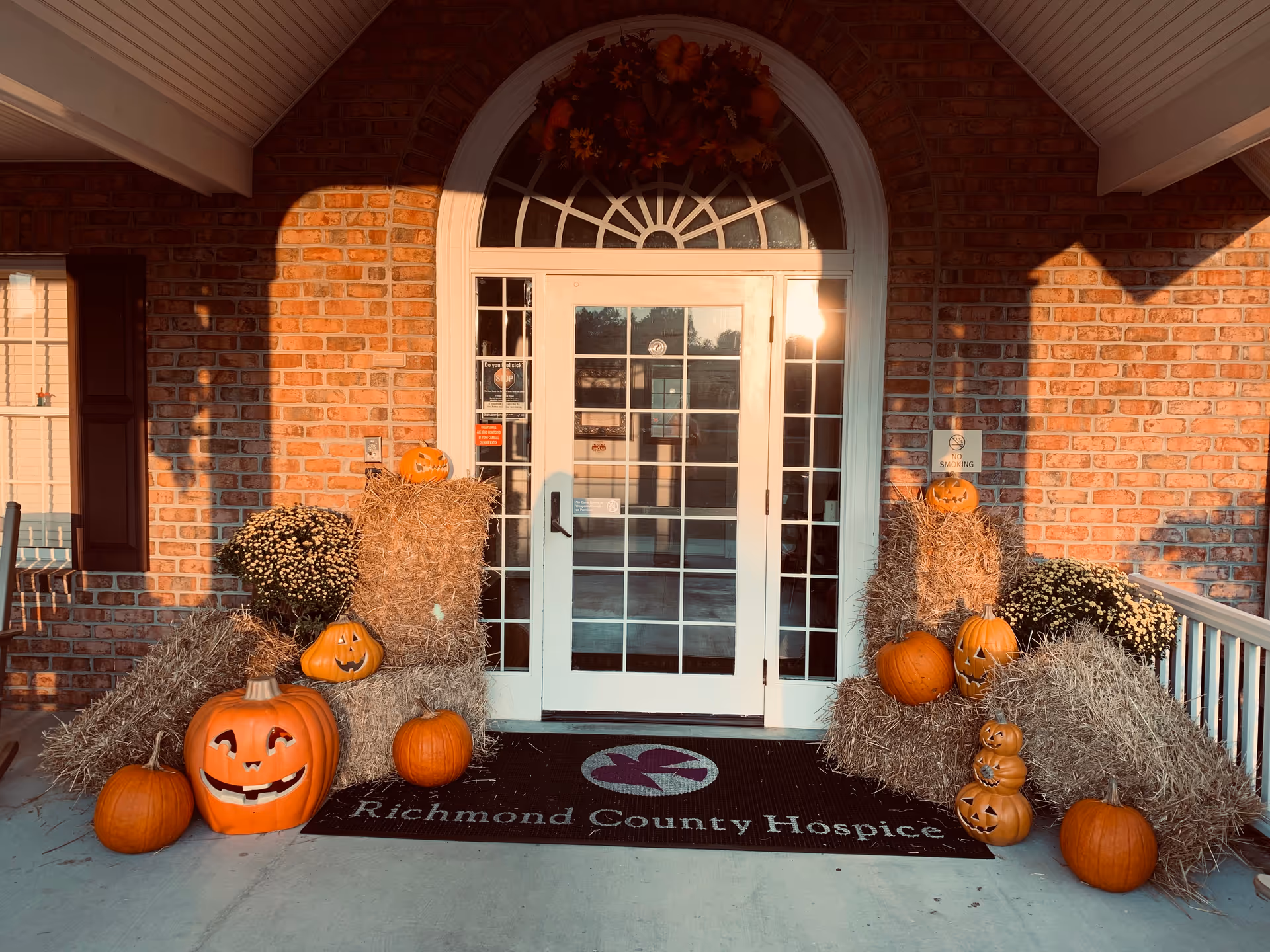 Brick building entrance with pumpkins and hay bales in autumn display outside Richmond County Hospice.