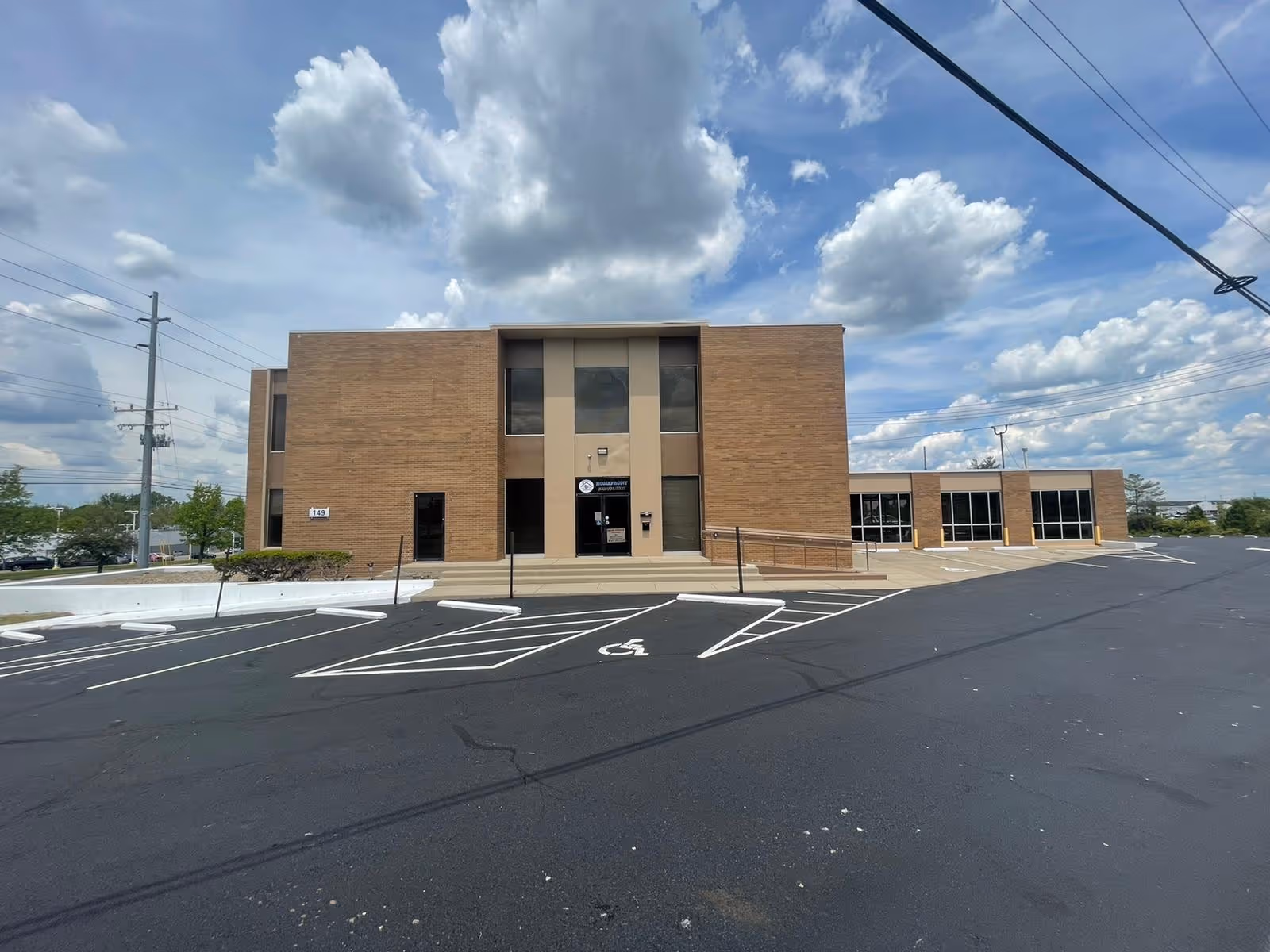 Exterior view of a brick nursing facility with a parking lot and accessible entrance.
