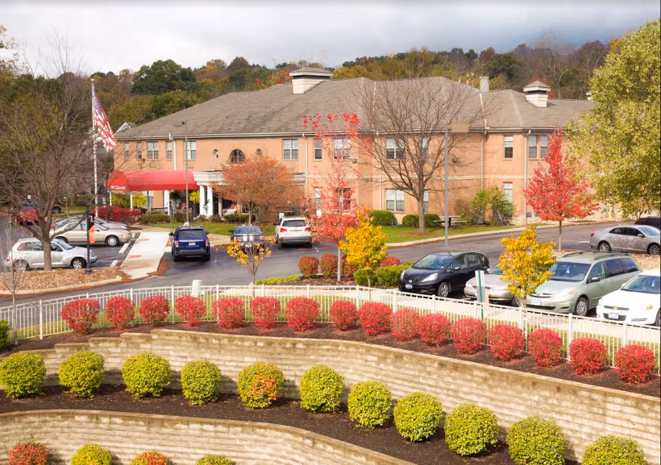 Front view of National Church Residences Chillicothe, brick building with autumn trees and landscaped terraces.