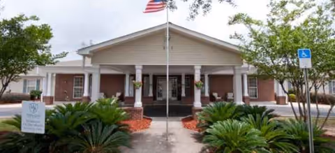 Front entrance of Brookdale Fort Walton Beach with flag and landscaped walkway.