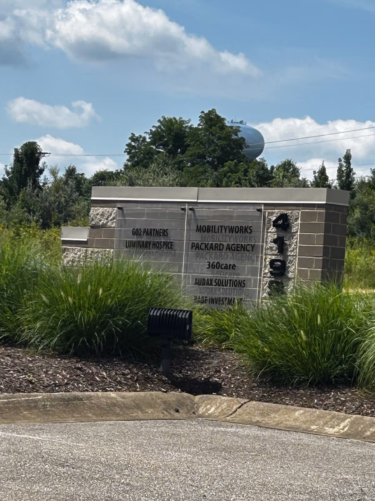 Exterior sign for MobilityWorks with partner company names amid landscaping