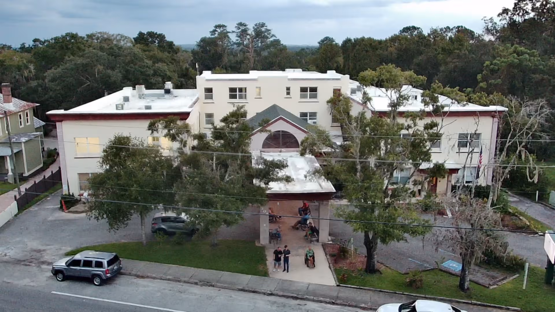A multi-story senior living facility with a central entrance and surrounding trees.