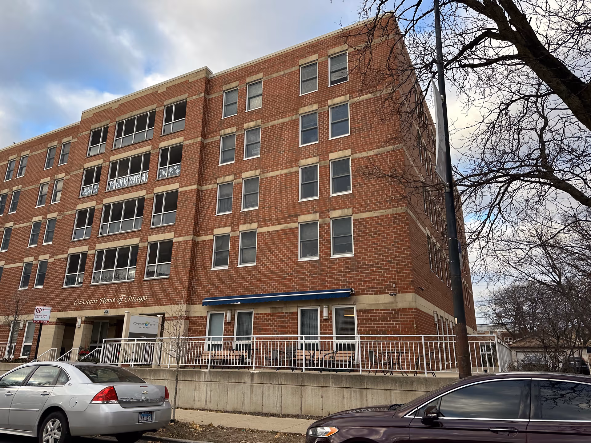 Front exterior of a multi-story red brick building labeled 'Covenant Home of Chicago' with parked cars and leafless trees.