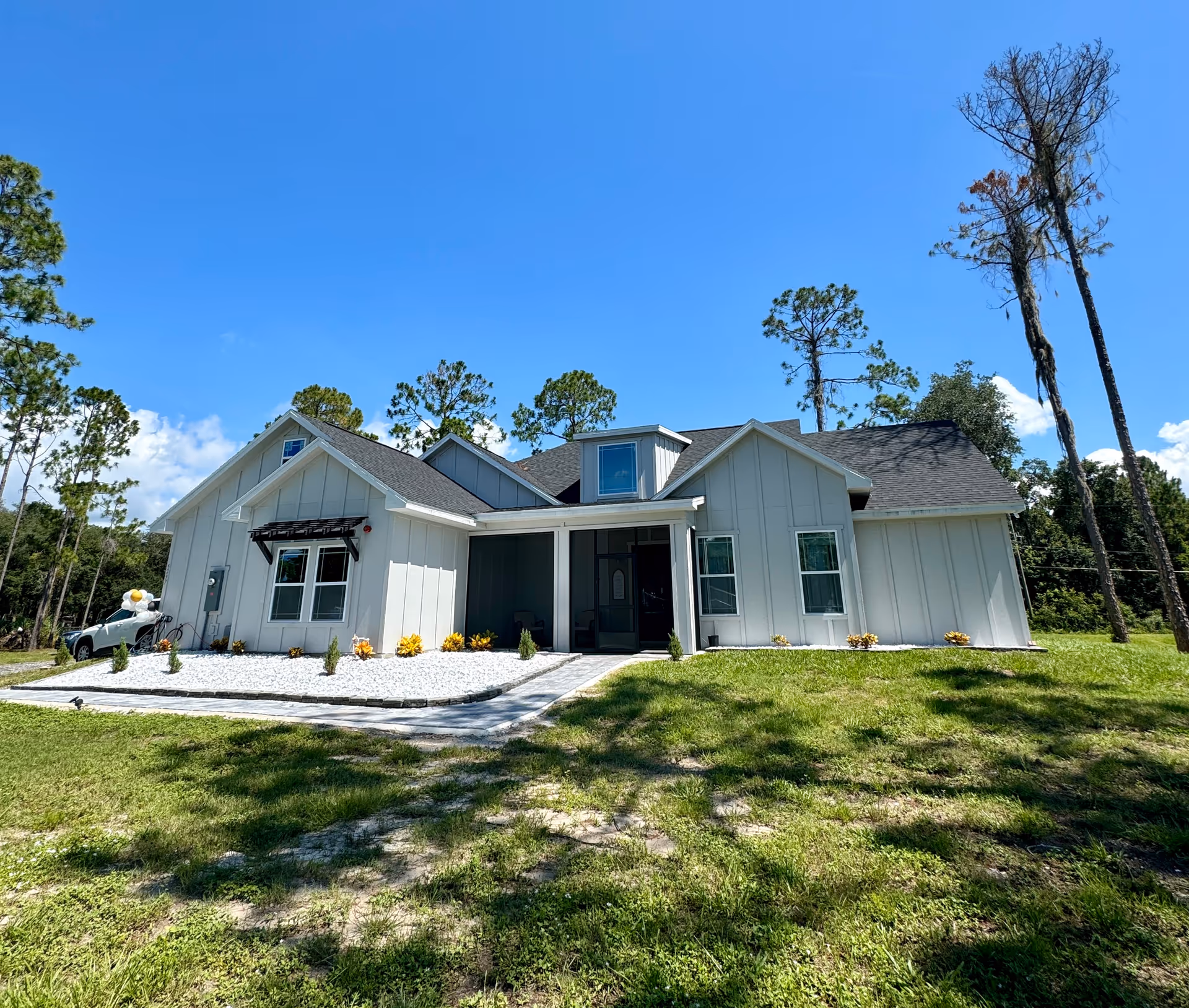 Front view of a modern white, single-story house with a well-kept lawn.