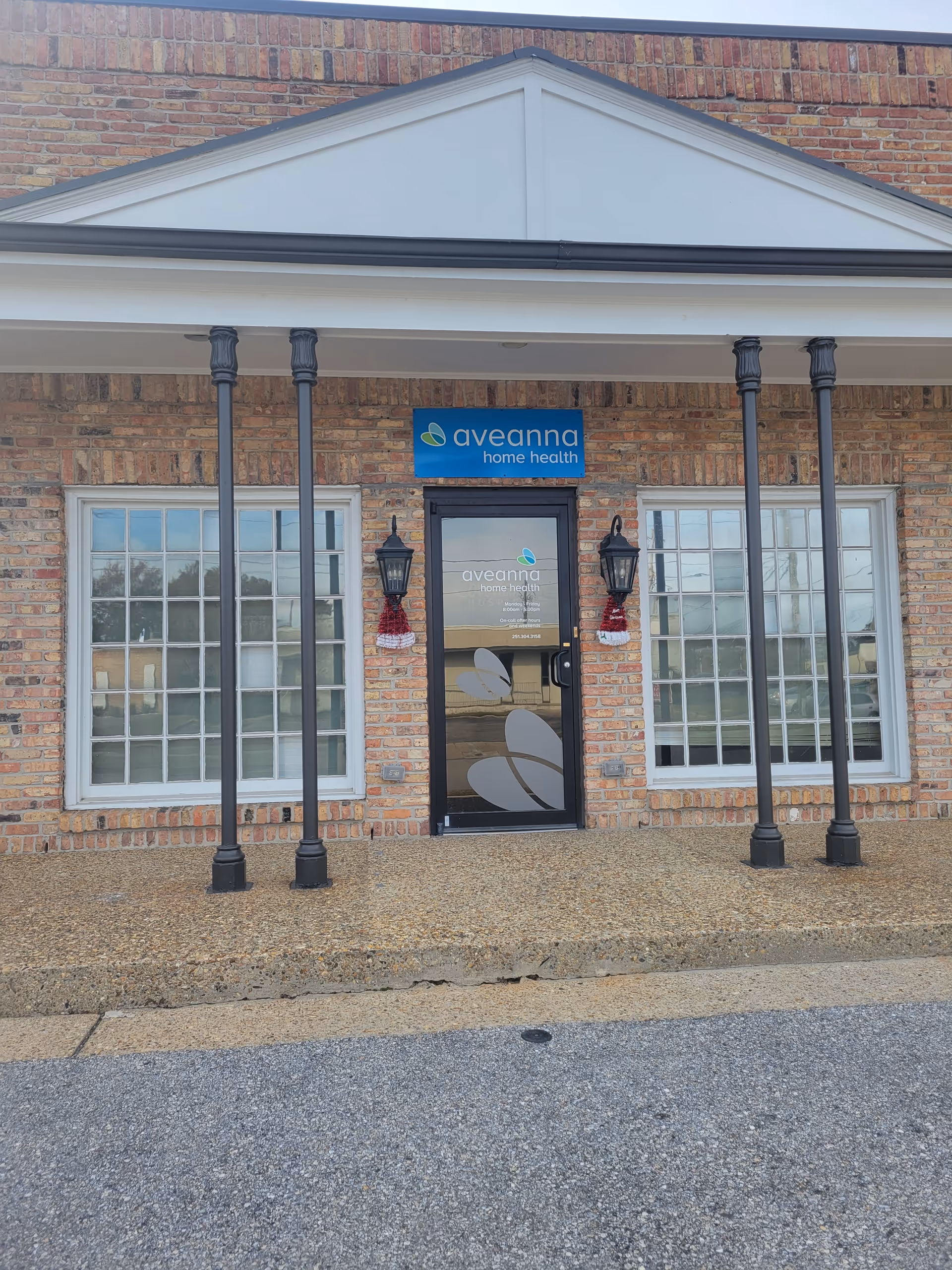 Brick storefront with Aveanna Home Health sign, double windows, and a glass door.
