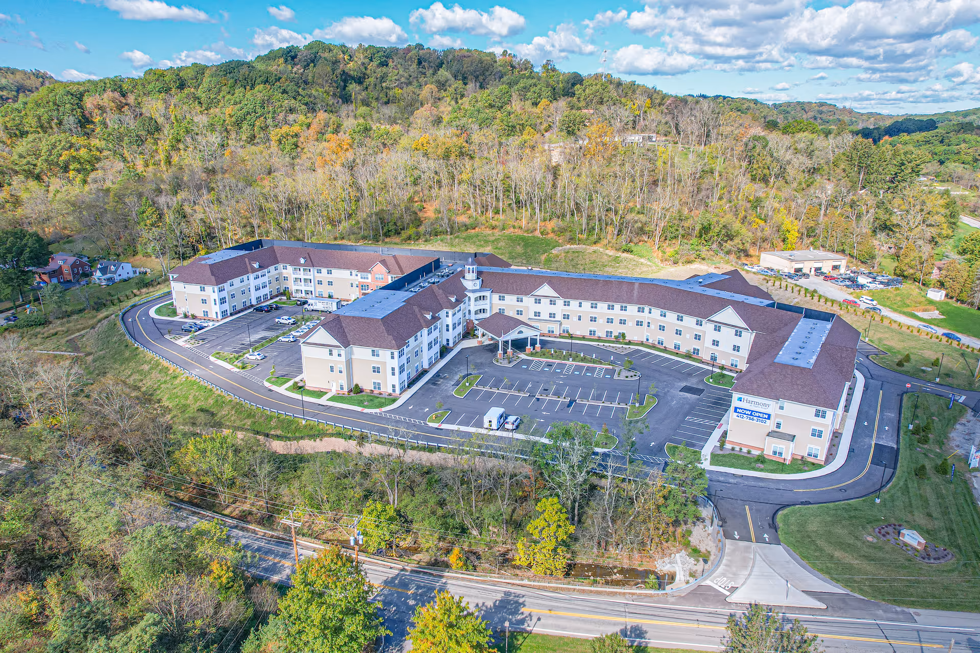 Aerial view of Harmony at Harts Run senior living campus with parking and surrounding woods