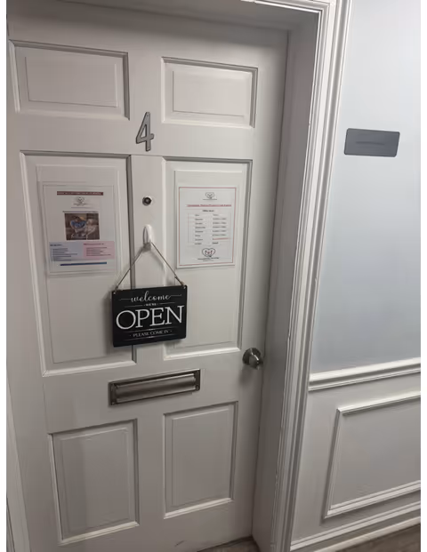 White hallway door marked 4 with posted notices and an OPEN sign in a senior facility.