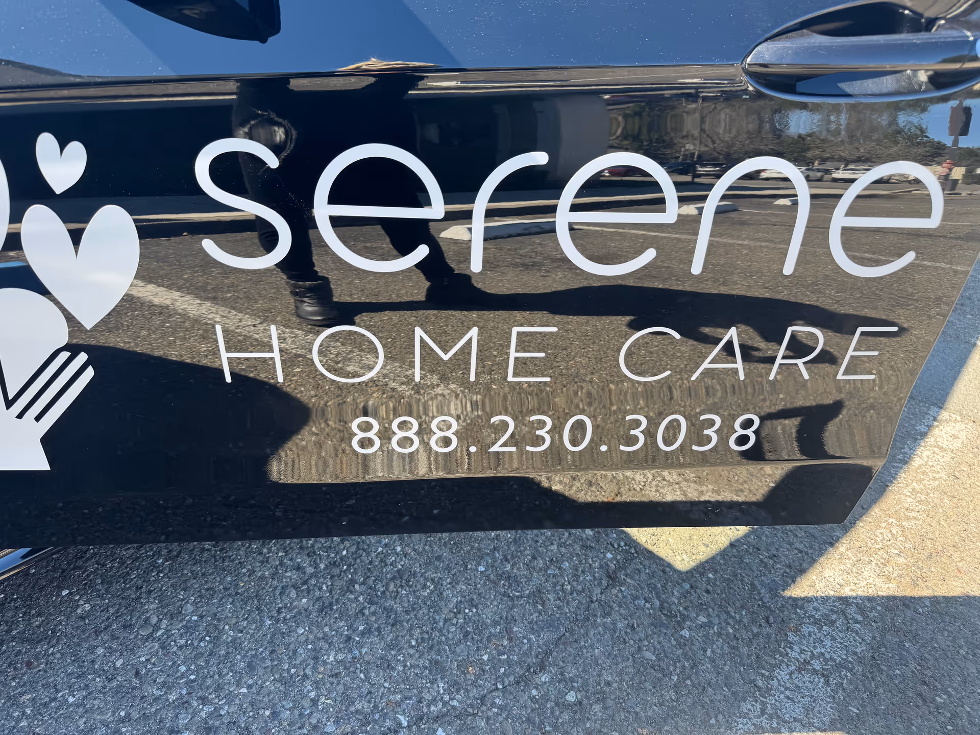 Side of a black van displaying Serene Home Care branding and phone number.