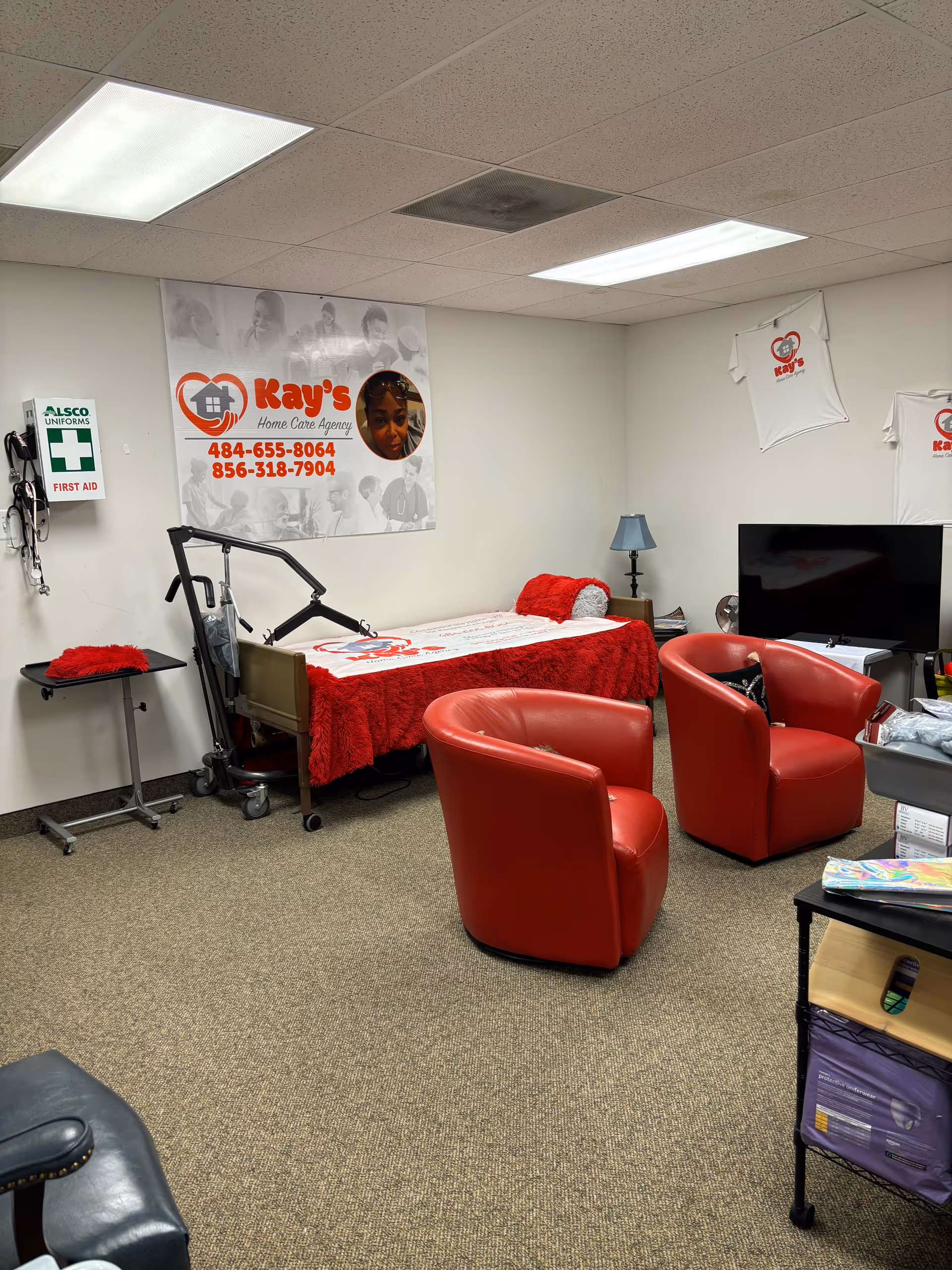 A care room with a hospital bed, red chairs, and medical equipment.
