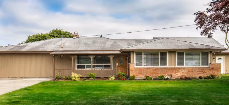 Front view of a single-story senior living home with brick accents and a green lawn.