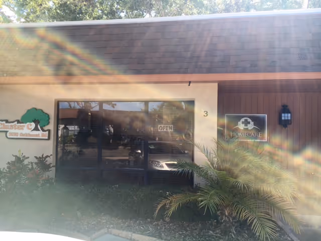 Front entrance of a senior home care facility with glass doors and surrounding plants.