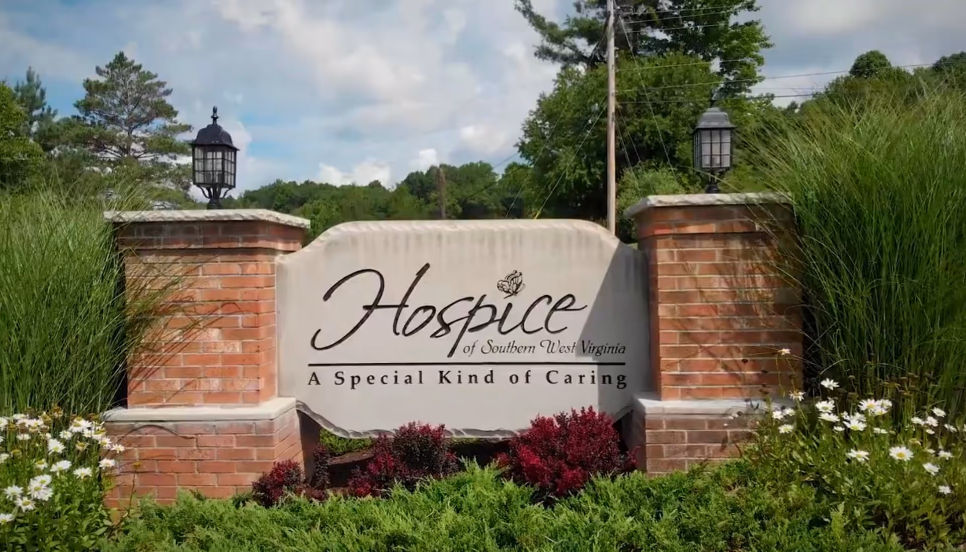 Stone sign reading Hospice of Southern West Virginia with brick pillars and landscaping at entrance.