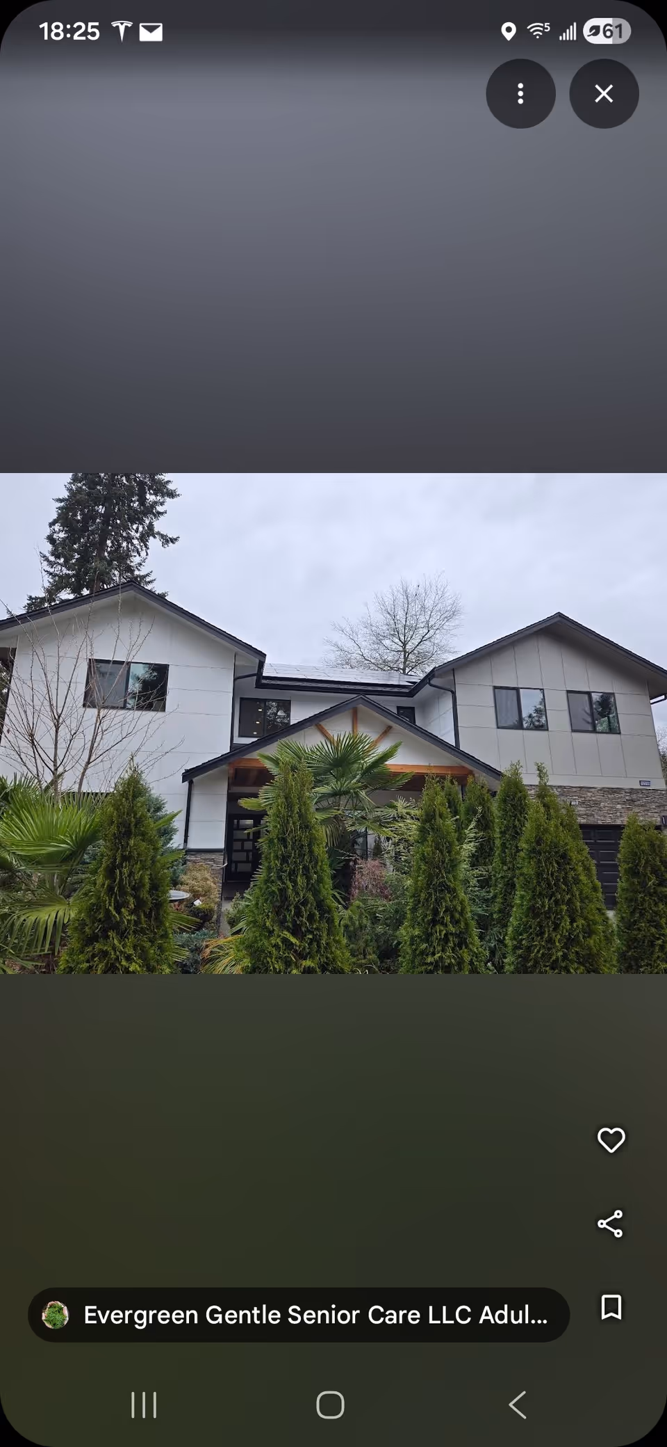 Front view of a two-story senior care facility with manicured evergreens and landscaping.
