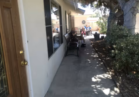 Outdoor walkway of Acorn Oaks Manor I with residents seated on benches.