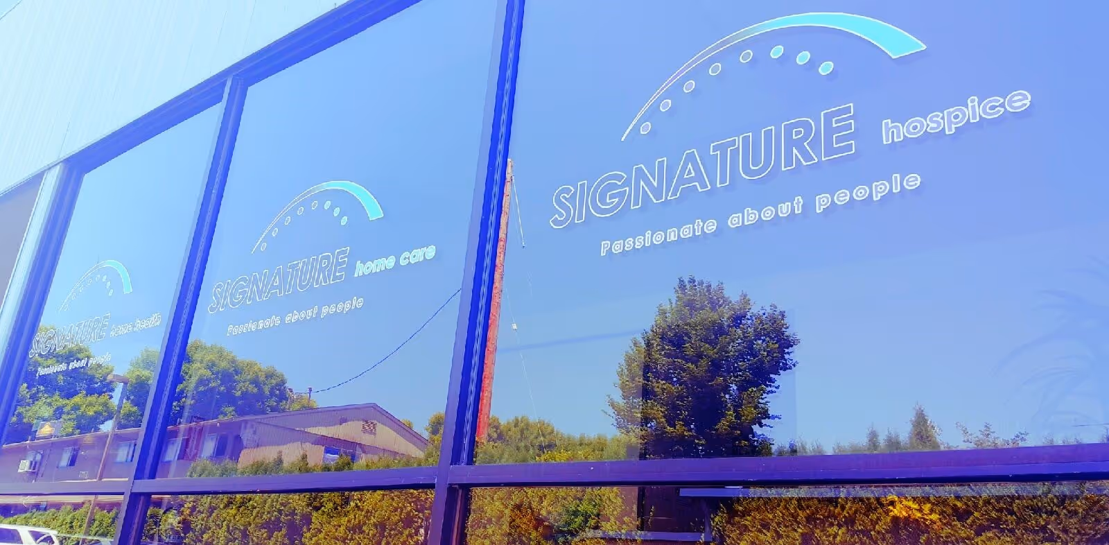 Exterior of a glass-front building with Signature hospice signage on the windows.