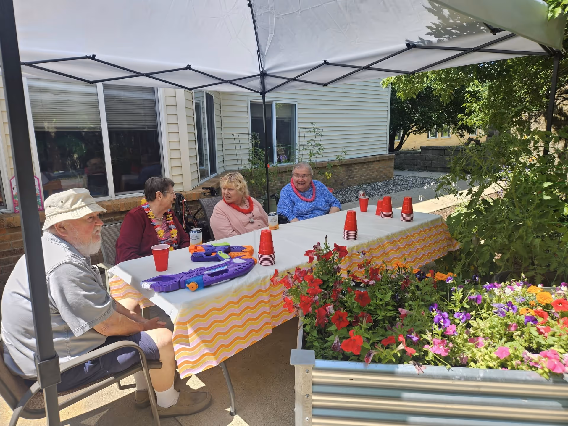 Pleasant View Estates residents sit at a table under a canopy on a sunny outdoor patio.