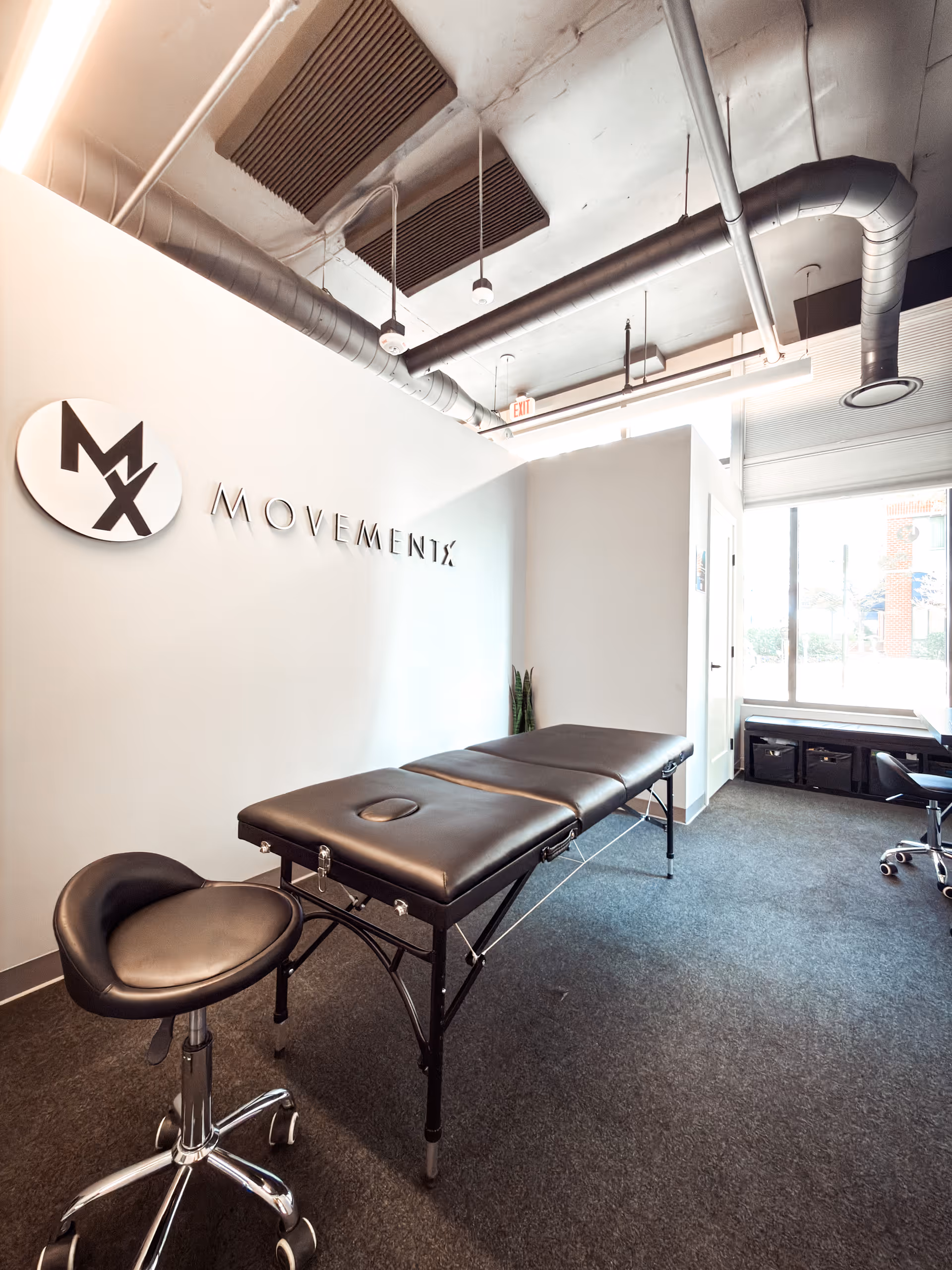 Interior of a physical therapy room with a treatment table and Movements sign on the wall.