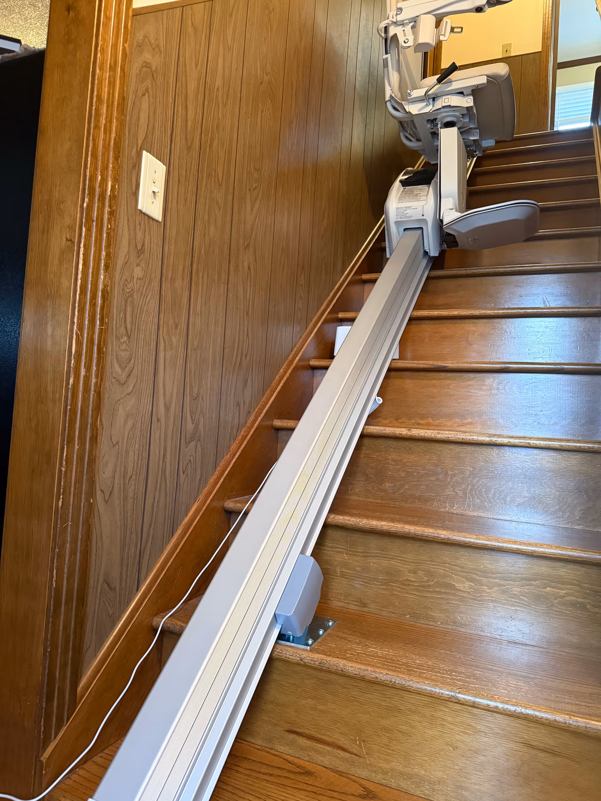 Interior staircase in a senior living facility with a mounted stairlift along wooden walls.