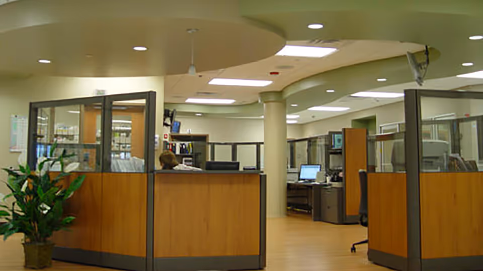 Reception area at a hospital with wood-paneled cubicles and computers.