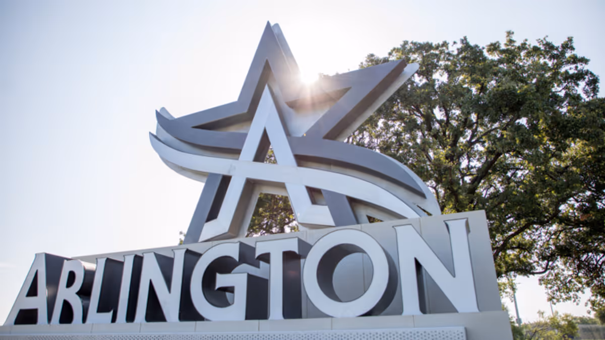 A large Arlington sign with a star sculpture and trees behind on a sunny day.
