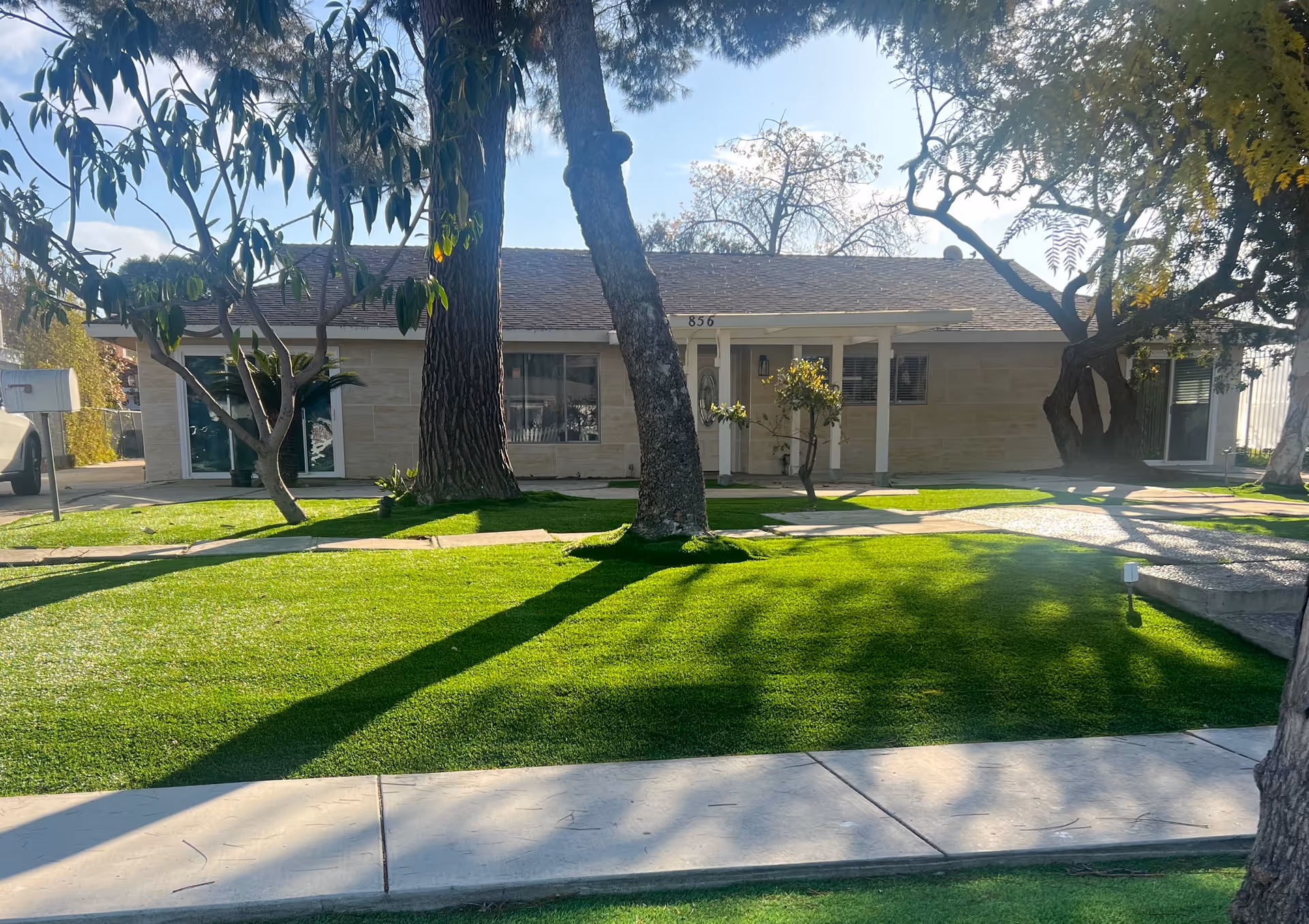 Exterior view of Coastal Comfort Assisted Living with a manicured lawn and trees.