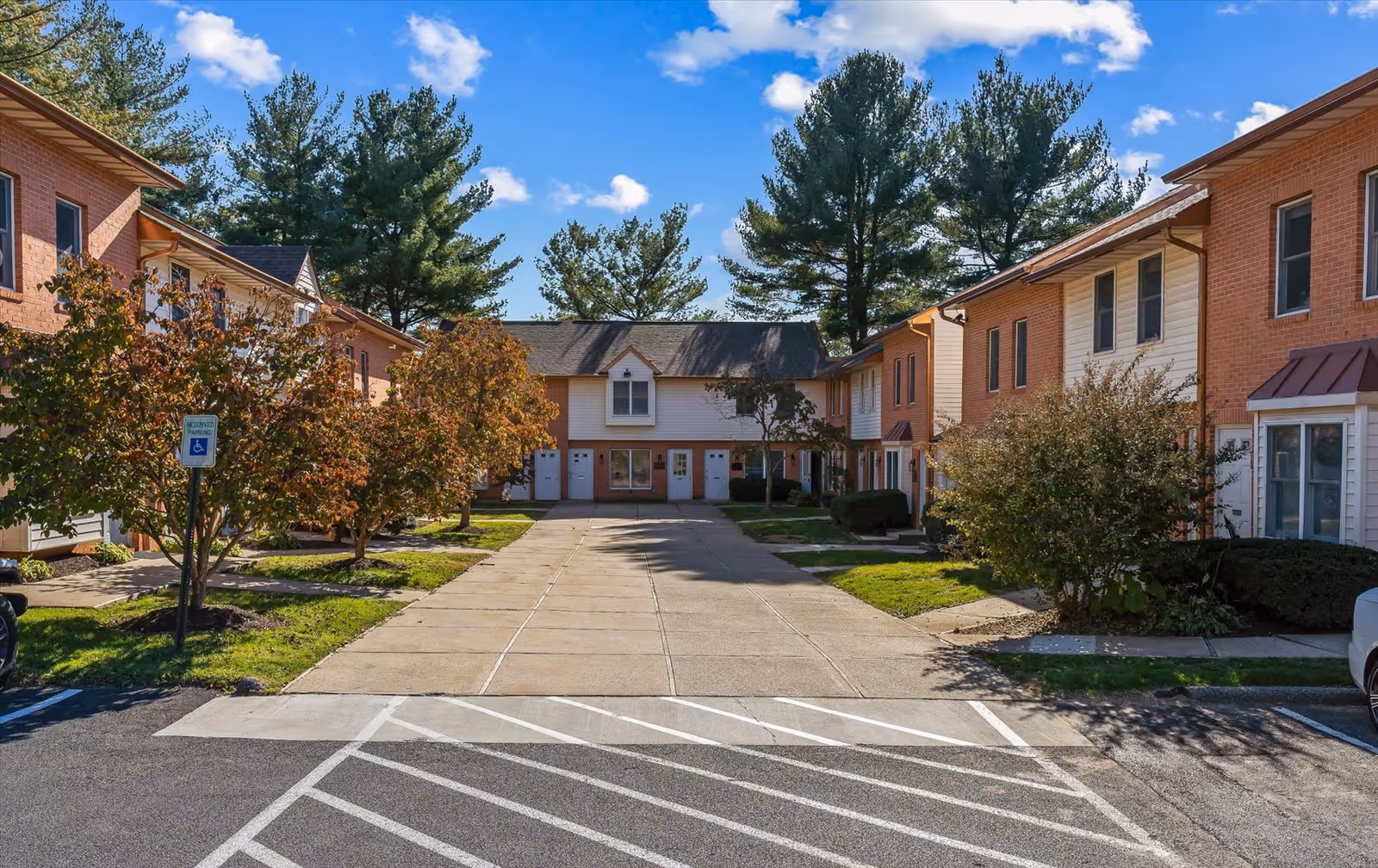 Exterior view of a senior living campus with brick townhouses and a central walkway.