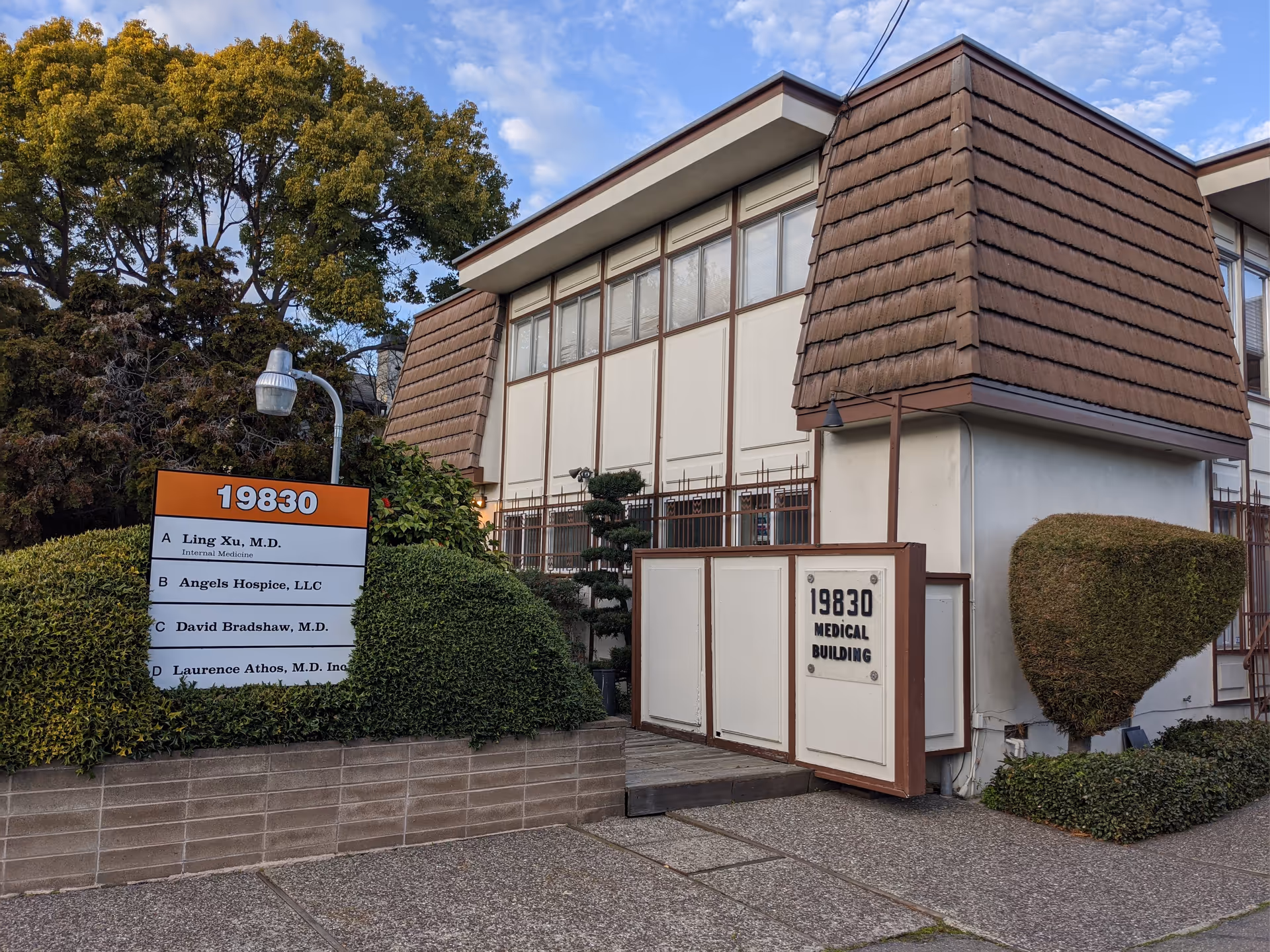 Exterior view of Angels Hospice medical building with large sign and address plaque.