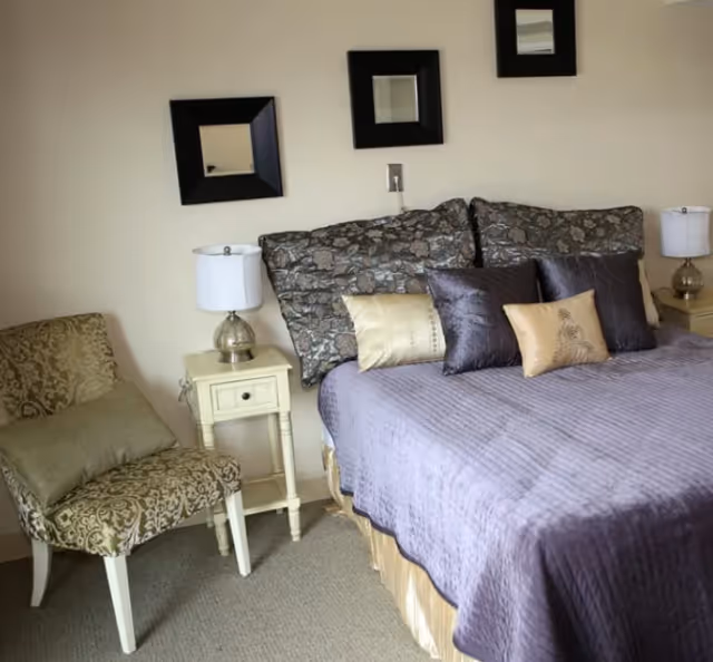 Bedroom at Sunflower Meadows #2 with purple bedding, lamps, and a patterned chair.