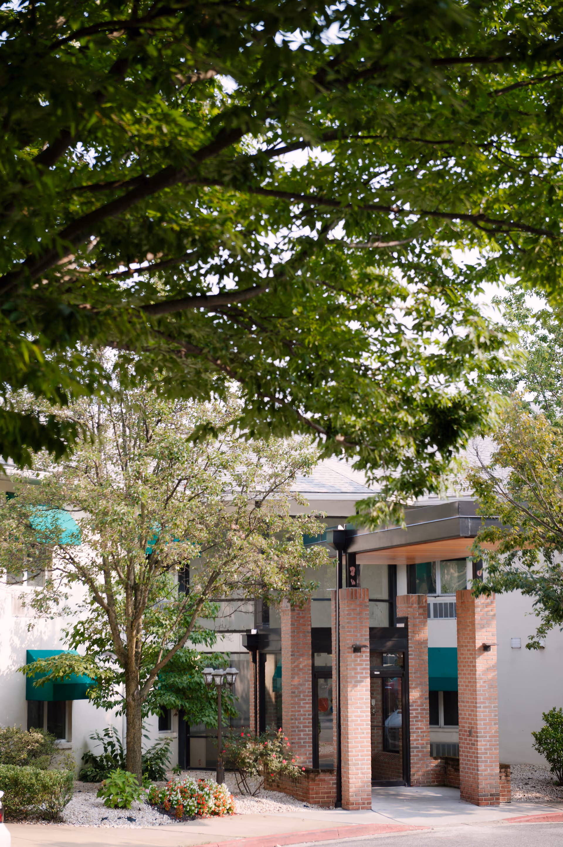 Exterior view of Autumn Lake Healthcare at Alice Manor entrance with brick columns and trees.