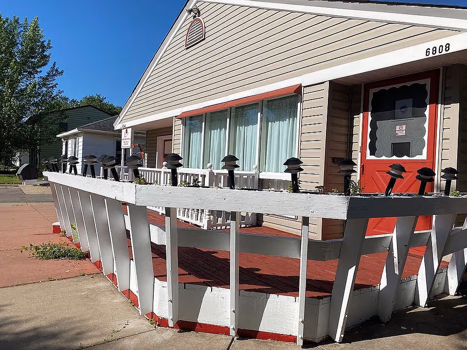Front exterior of Richfield Senior Suites featuring a white railing and red door.