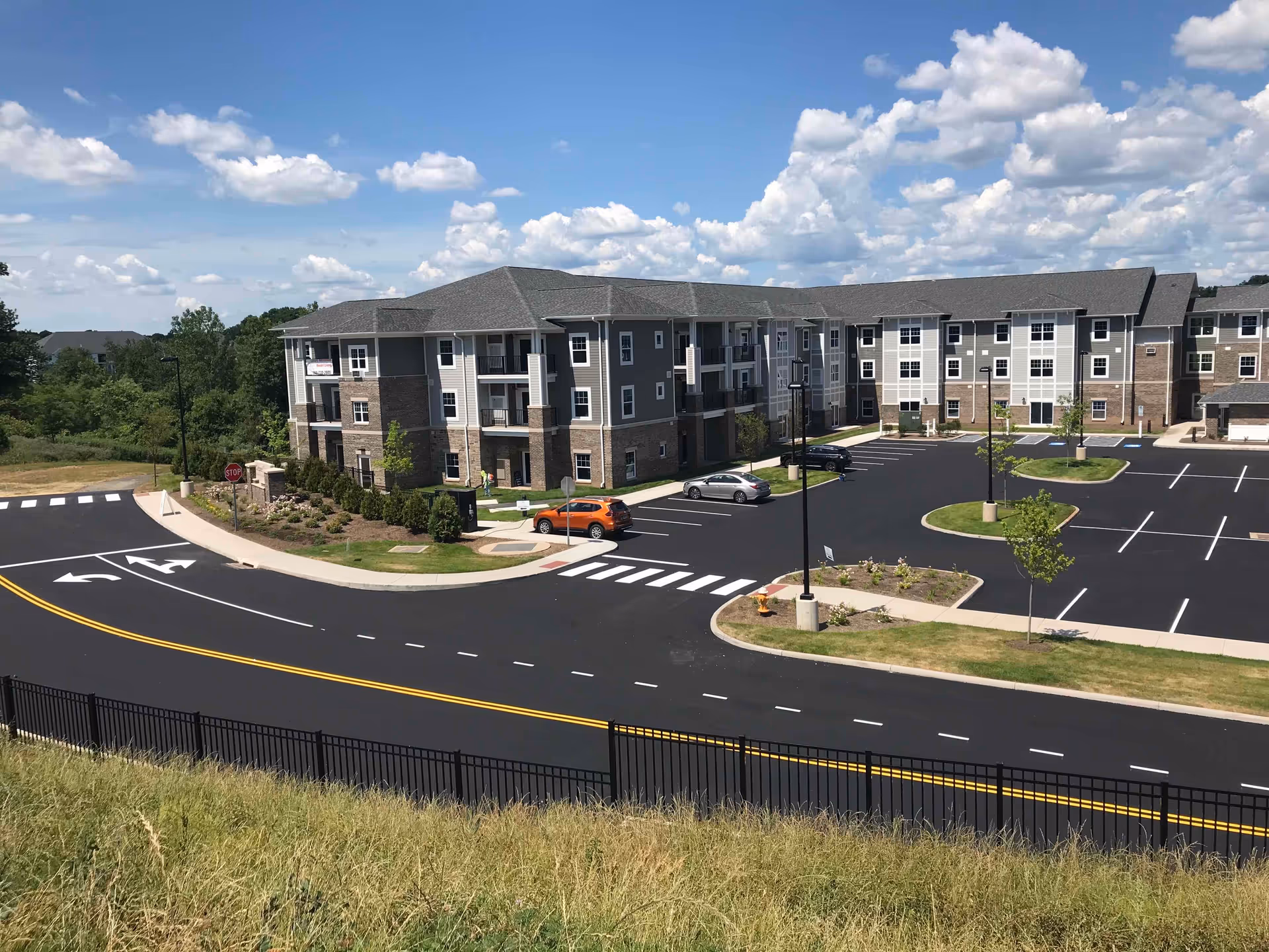 A modern, multi-story senior living building with a paved parking lot and landscaping.