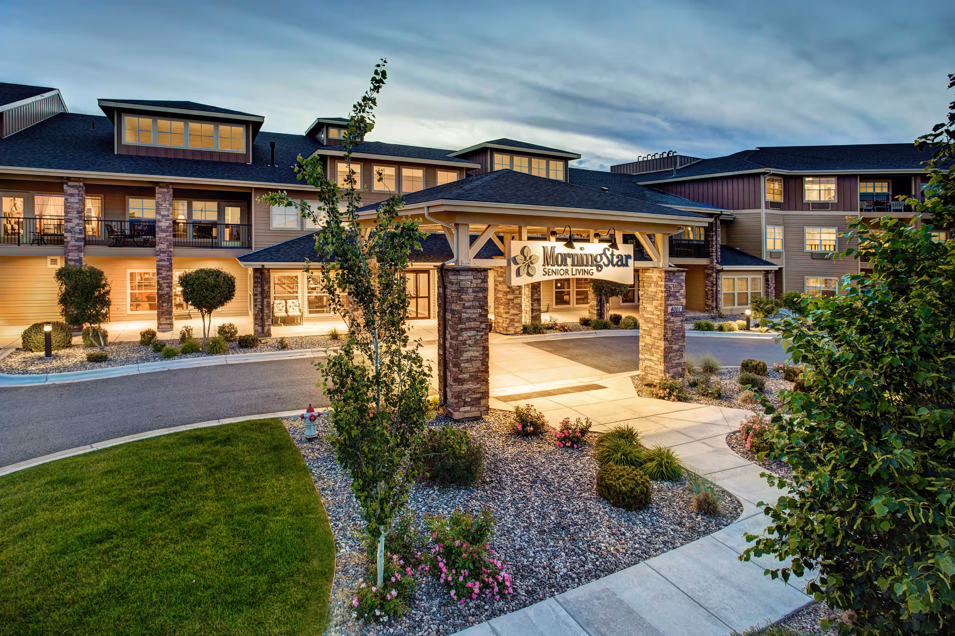 Front entrance of MorningStar Senior Living building with a covered porte-cochère, illuminated windows, and landscaped walkway at dusk.