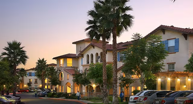 Sunset-lit senior living villas exterior with palm trees and a parking lot.