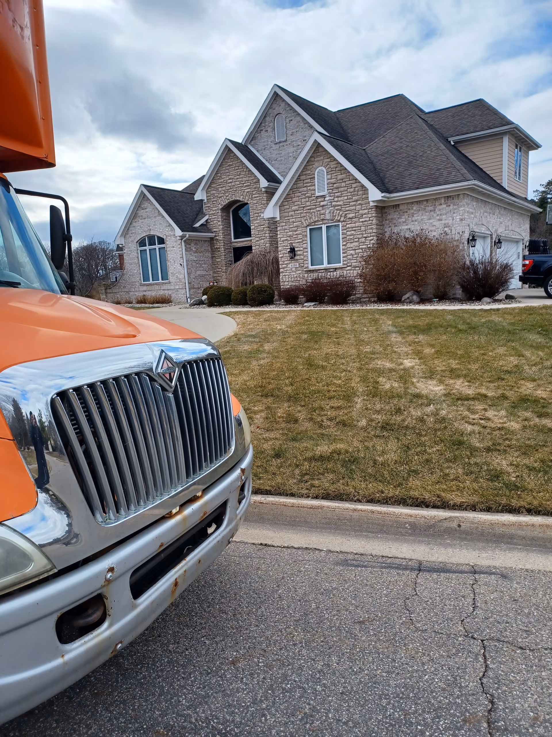 Orange truck parked on street in front of a stone-faced senior living building.