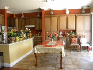 Bright kitchen and dining area with a central table and wooden cabinetry.